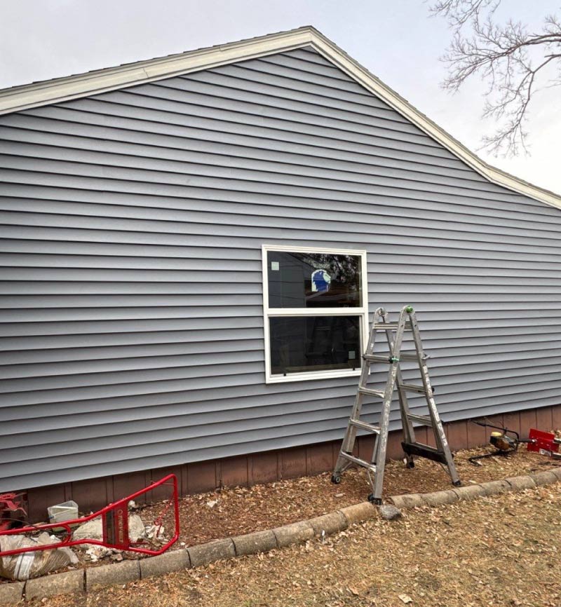 completed-window A newly installed, energy-efficient window on a home with fresh gray siding, showcasing professional craftsmanship.
