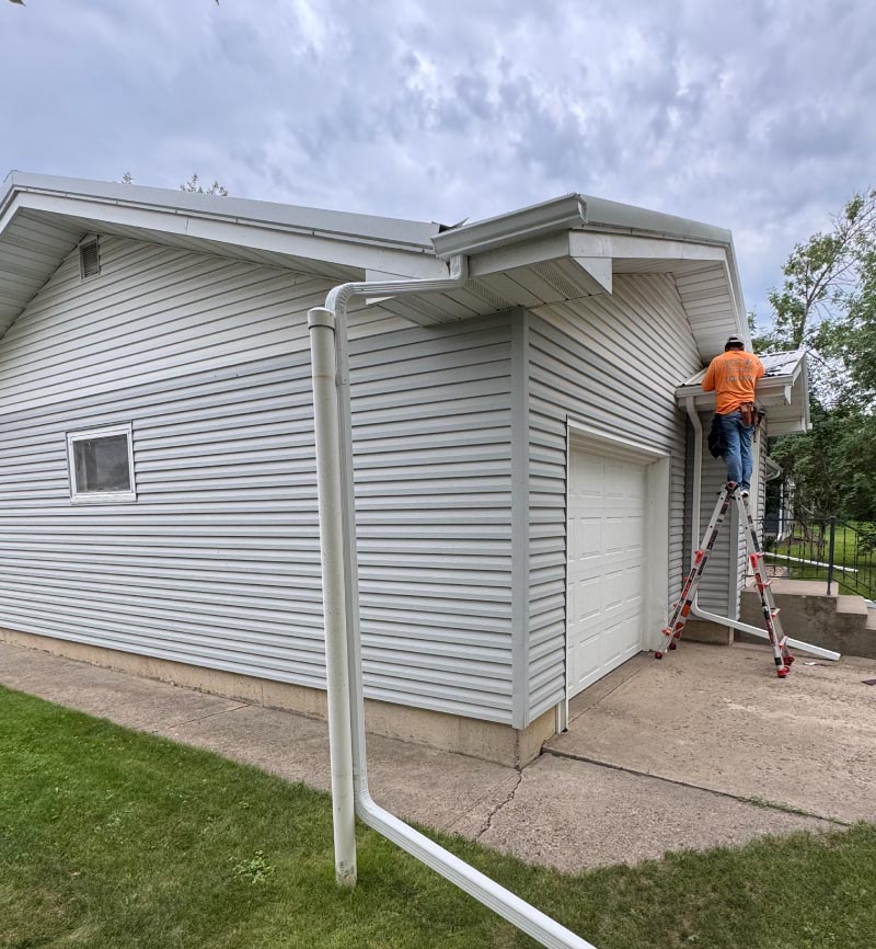 new-gutter-system Installation of a new, efficient white gutter system and downspout by a professional technician to ensure proper roof drainage and water management